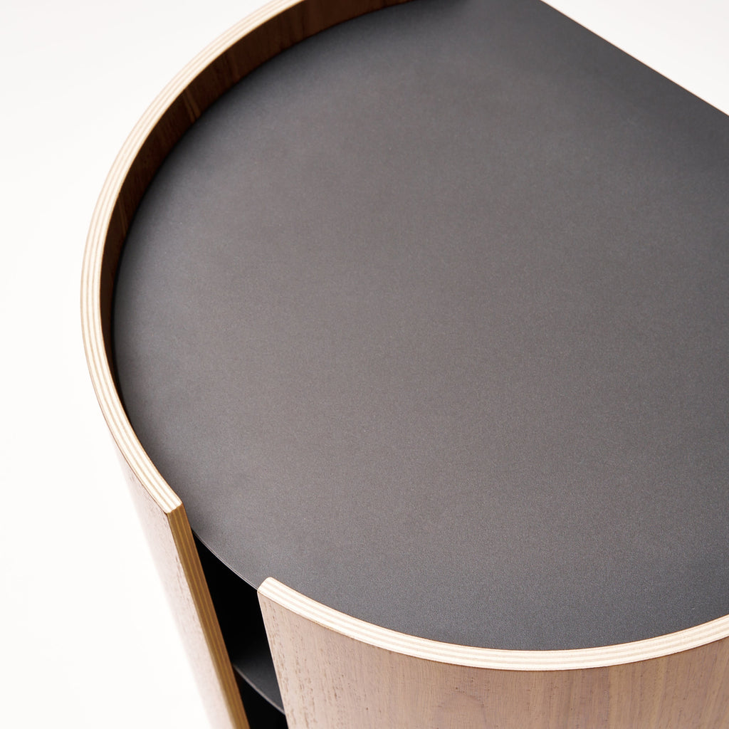 Apto Contour Side Table in walnut plywood and black powder-coated steel. SKU 10801. Bring style and function to any room with this modern three-tier steel and wood side table. Designed with your lifestyle in mind. The table features an opening in the back for easy cable management and charging. Balances modern steel surfaces with stylish molded plywood.