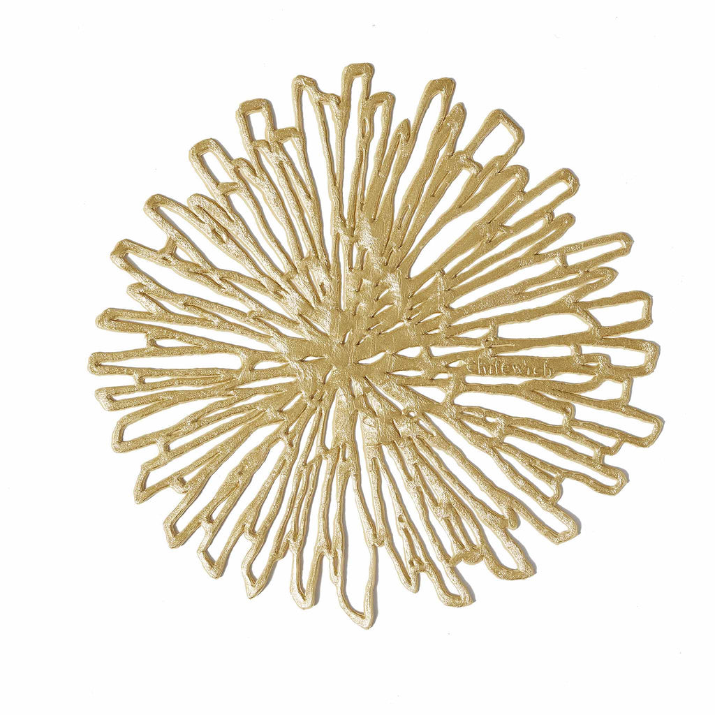 Chilewich Bloom Coaster Set in Glided/Brass. SKU 100566-001. Combining the organic exuberance of a chrysanthemum, the graphic refinement of a contour line sketch, and a modern palette of metallic hues, Bloom is a fresh interpretation of florals. 