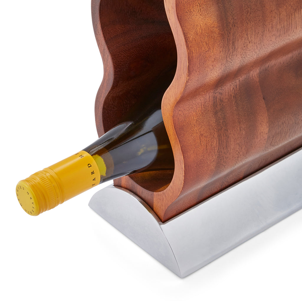 Resting on its Nambé Alloy base, the Curvo Wine Rack’s acacia wood form curves rhythmically to create spaces for four wine bottles. A beautiful and functional art piece, it can be displayed from the side or the front for two distinct effects. Made of Acacia wood and Nambé Alloy.