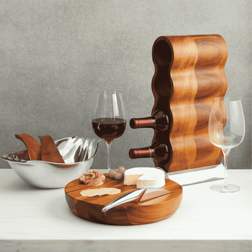 Resting on its Nambé Alloy base, the Curvo Wine Rack’s acacia wood form curves rhythmically to create spaces for four wine bottles. A beautiful and functional art piece, it can be displayed from the side or the front for two distinct effects.