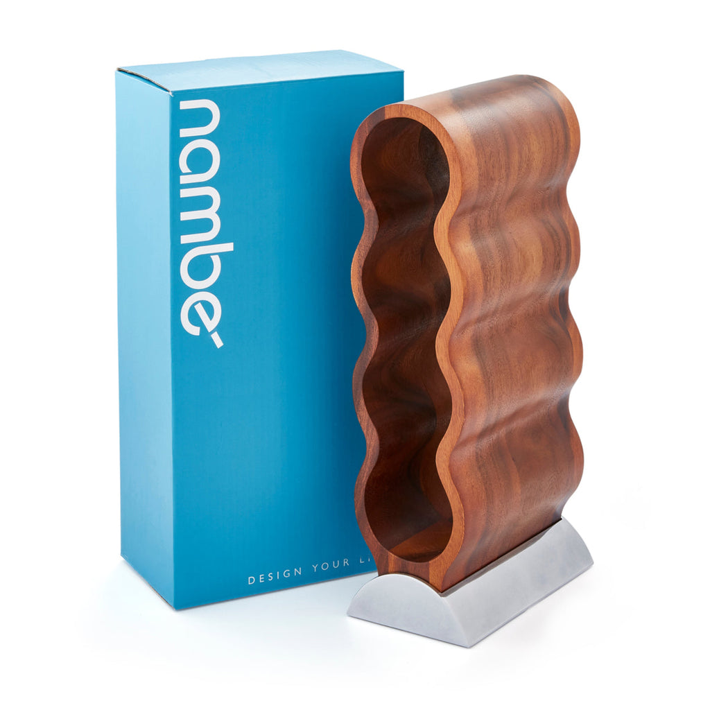 Resting on its Nambé Alloy base, the Curvo Wine Rack’s acacia wood form curves rhythmically to create spaces for four wine bottles. A beautiful and functional art piece, it can be displayed from the side or the front for two distinct effects.
