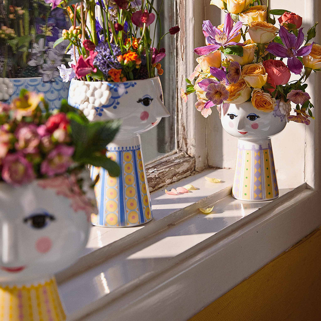 The Eva series is a reinterpretation of Bjørn Wiinblad’s original vases with their characteristic smiling woman’s face that he himself called Eva. The face with the almond-shaped eyes and pointed nose is Wiinblad’s original design, and the colourful dress patterns are an interpretation of Bjørn Wiinblad’s archived illustrations. 