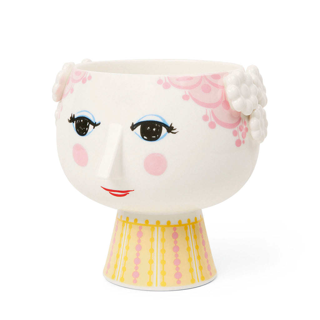 Bjørn Wiinblad represents everything that is crazy, quirky, creative and wonderful. And with the beautiful and smiling Eva flowerpot from Bjørn Wiinblad with pink hair and a bright pink and yellow dress, you can create a quirky, colourful vibe throughout your home. The flowerpot measures 14.5 cm in height and with a diameter of 15.5 cm, it is perfect for displaying herbs, trendy succulents, small plants or arranged flower compositions. 