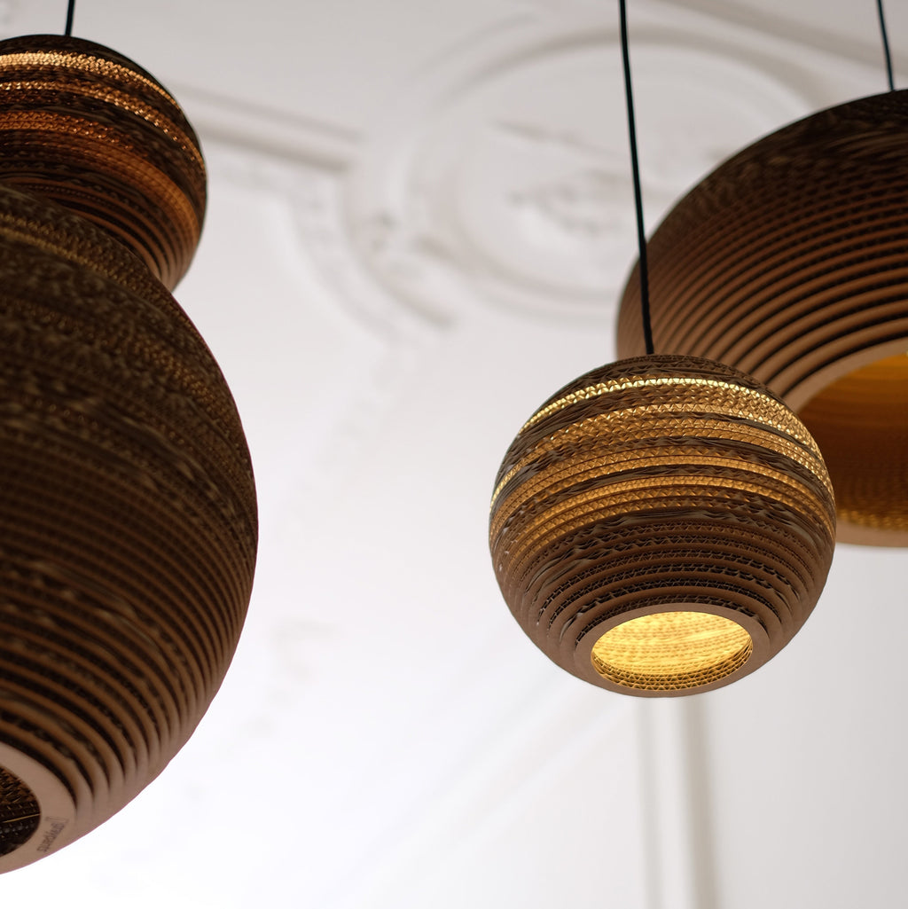 Handcrafted from recycled or pure white cardboard, Graypants’ flagship Scraplights series provides warm, intimate, and functional lighting for any occasion or type of space. Tough and elegant, each shade is precision cut with a laser (natural & blonde shades) or precision cut on advanced machinery (white shades) and assembled by hand using a nontoxic adhesive. All Scraplights are treated with an environmentally friendly fire retardant and are inscribed with the name of their artisan maker!