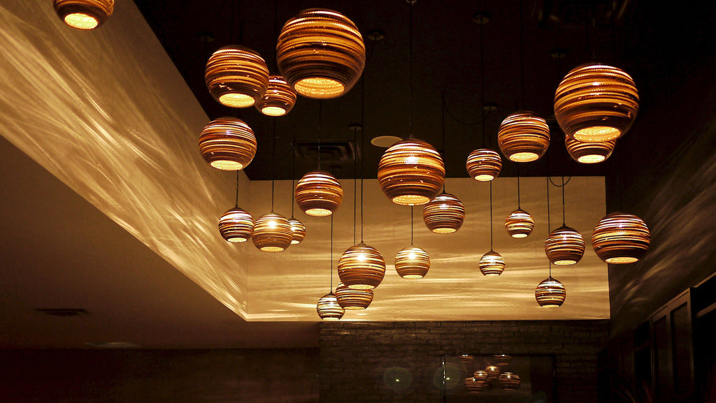 Scraplights are constructed from natural recycled cardboard precision cut by a laser. This gives the edges their classic dark appearance and enhances the warm light projected through the corrugation. The classic series includes many of the best-selling models such as the Moon and Disc, along with newer designs like the Hive and Nest.