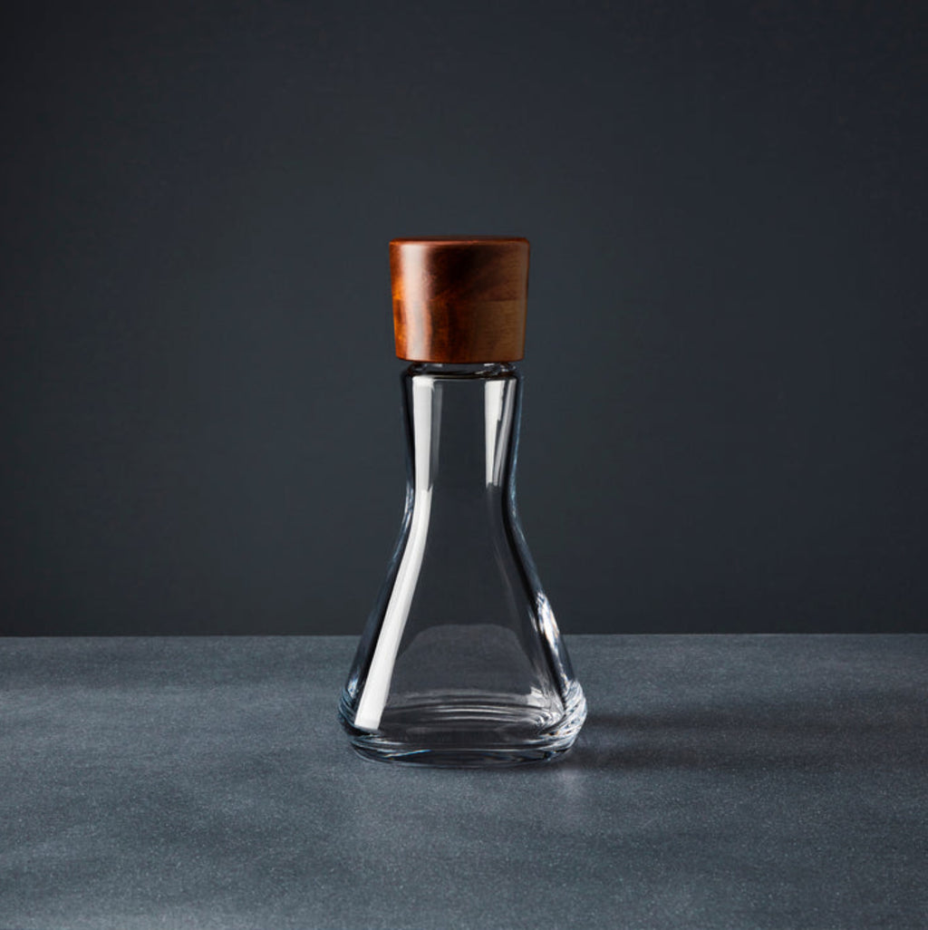 Nambe Vie Decanter – 10” designed by Chris Granneberg. The combination of the Vie Decanter’s square, glass body and rounded, wood stopper make this piece a style-standout. 