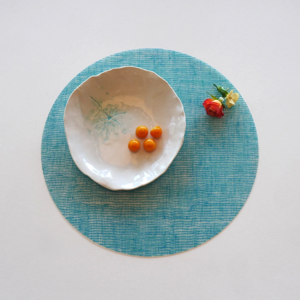 Round Placemat : Linen - Seafoam by Modern-Twist. UPC# 854796002041. This forgiving placemat protects your surfaces from heat & water damage with silky soft, memory-free silicone that never wears or tears. The non-porous & germ-free material repels the biggest spills & wipes clean with ease, leaving you free to enjoy the subtle designs & rich colors for many years to come.