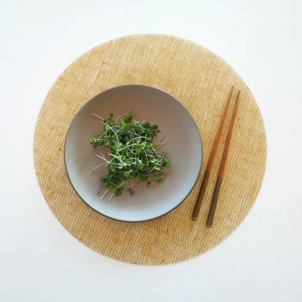 Round Placemat : Linen - Straw by Modern-Twist. Made from plastic-free silicone & hand silk-screened with nature-inspired designs, the modern-twist cocoon print placemat delivers eco-friendly, elegant style to your home. Bring botanical beauty to your table with this soft, beautifully translucent pattern that enhances any surface while keeping lead, latex, phthalates, BPAs, & other harsh chemicals far away from your dinner. This forgiving placemat protects your surfaces from heat & water damage.