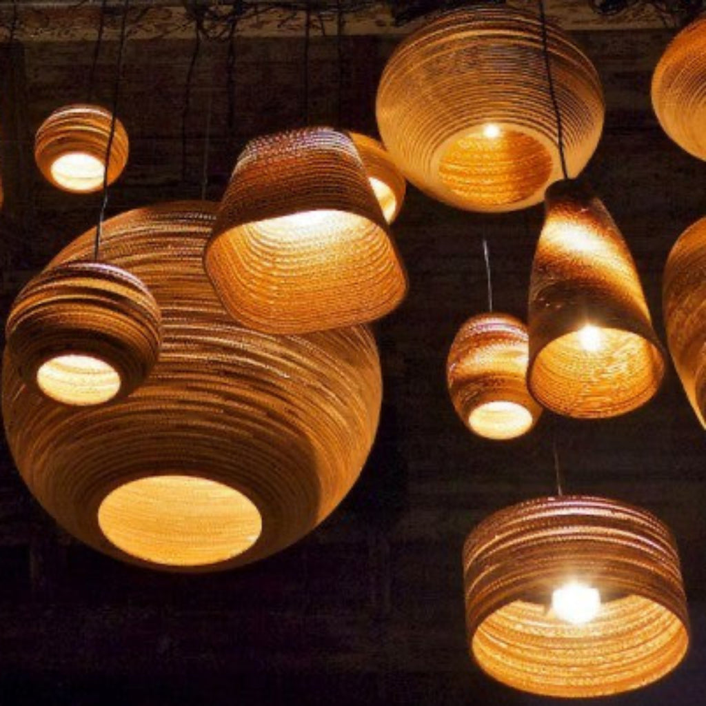 Handcrafted from recycled or pure white cardboard, Graypants’ flagship Scraplights series provides warm, intimate, and functional lighting for any occasion or type of space. Tough and elegant, each shade is precision cut with a laser (natural & blonde shades) or precision cut on advanced machinery (white shades) and assembled by hand using a nontoxic adhesive. All Scraplights are treated with an environmentally friendly fire retardant and are inscribed with the name of their artisan maker!