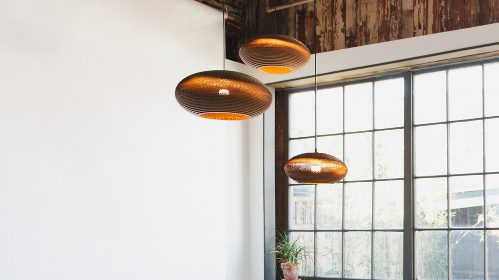 Scraplights are constructed from natural recycled cardboard precision cut by a laser. This gives the edges their classic dark appearance and enhances the warm light projected through the corrugation. The classic series includes many of the best-selling models such as the Moon and Disc, along with newer designs like the Hive and Nest.
