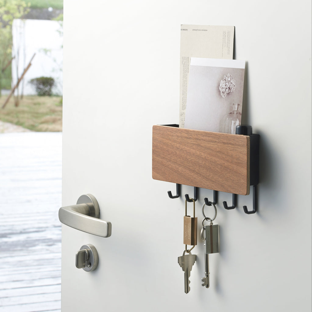 Yamazaki Home Rin Steel Wood Magnetic Key Rack comes with screws and anchors for wall mounting or with a magnet to adhere to a metal door (or the side of your fridge). 