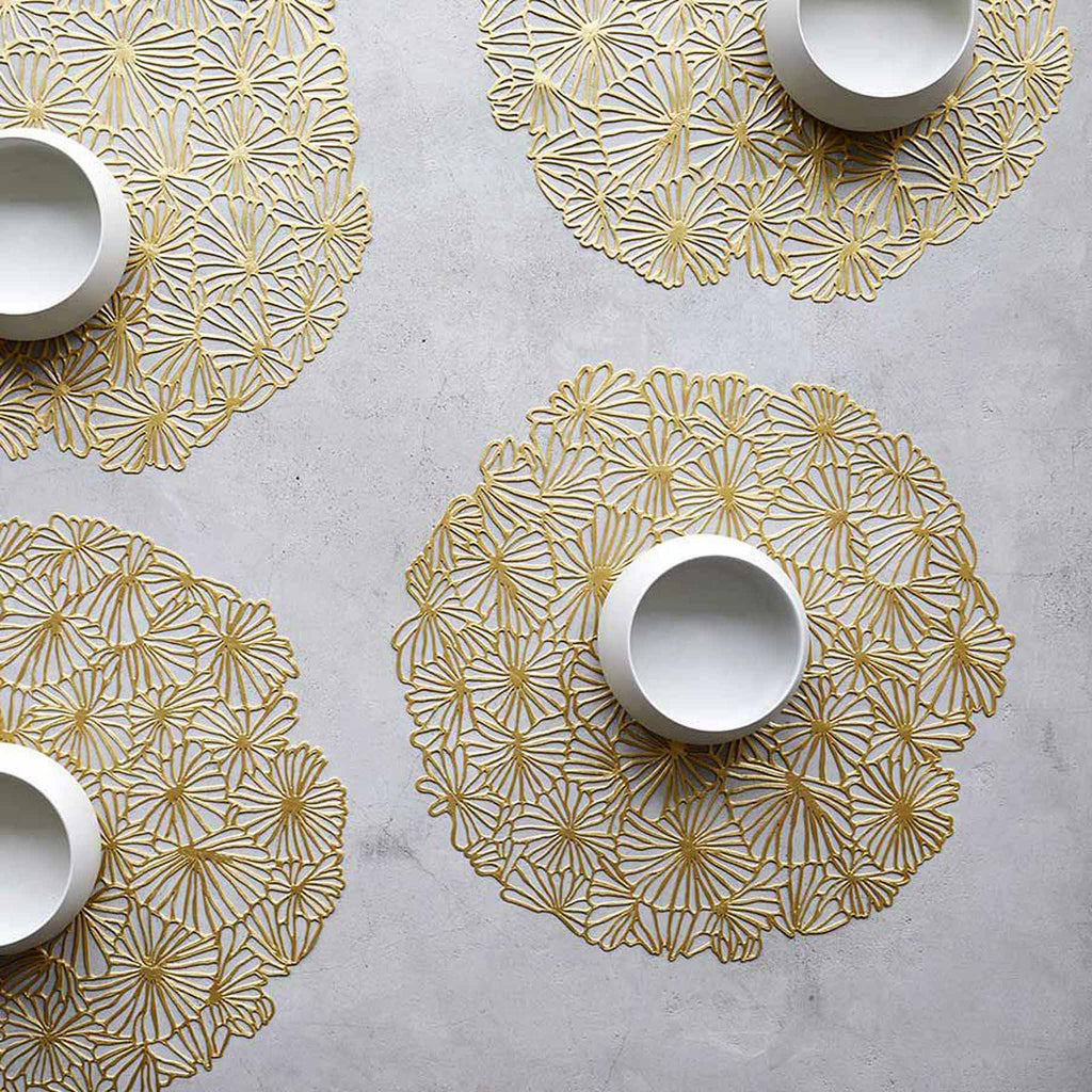 Pressed Daisy ©2022 Chilewich gilded. SKU 100716-002. UPC 667880942167. Taking the playful form of a tightly clustered bouquet of daisies as viewed from above, this flexible openwork placemat acts as a decorative base for whatever is placed on top.