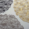 Pressed Daisy ©2022 Chilewich. Taking the playful form of a tightly clustered bouquet of daisies as viewed from above, this flexible openwork placemat acts as a decorative base for whatever is placed on top. It is delicate in appearance yet surprisingly resilient: a contemporary interpretation of both classic florals and the ancient craft of lacemaking. 