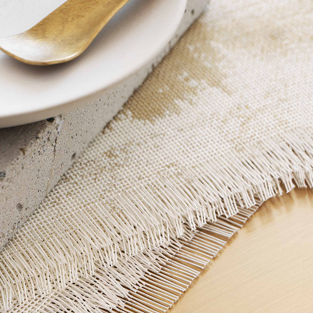 Chilewich Imprint characterized by a linen-like texture with a faint print. The edges have a delicate fringe finish. Chilewich Imprint in antique gold. SKU 100368-002. UPC 667880920042.